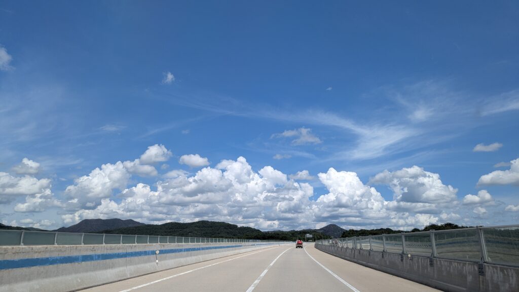 a very clear day with blue sky and fluffy clouds seen from the road