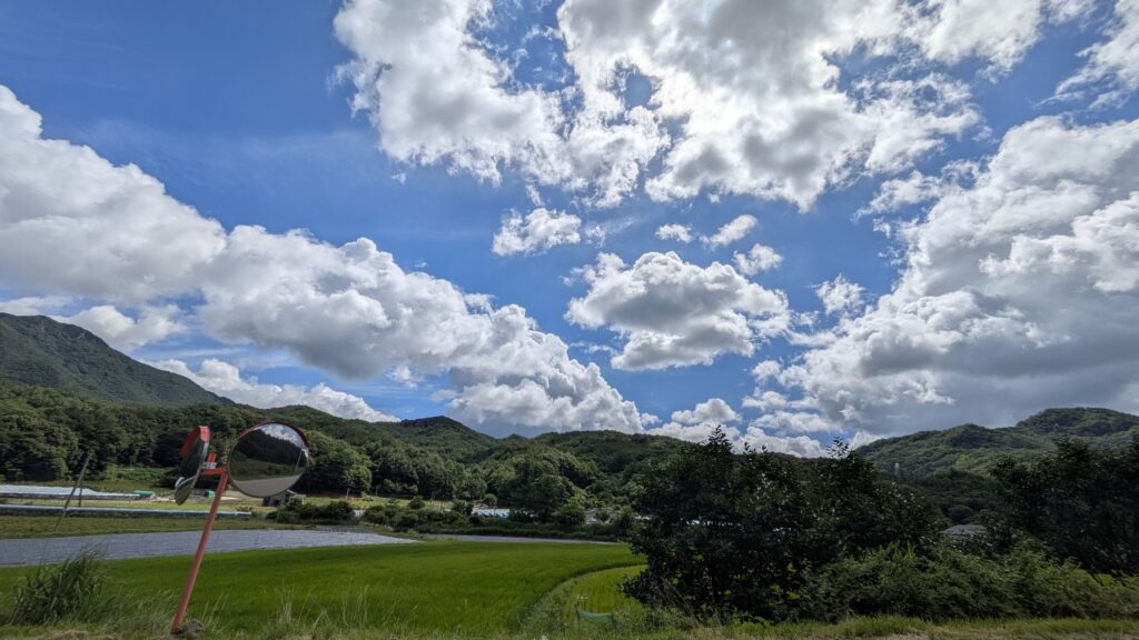 a beautiful view of the blue sky with clouds spreading out and rice paddies and blue mountains